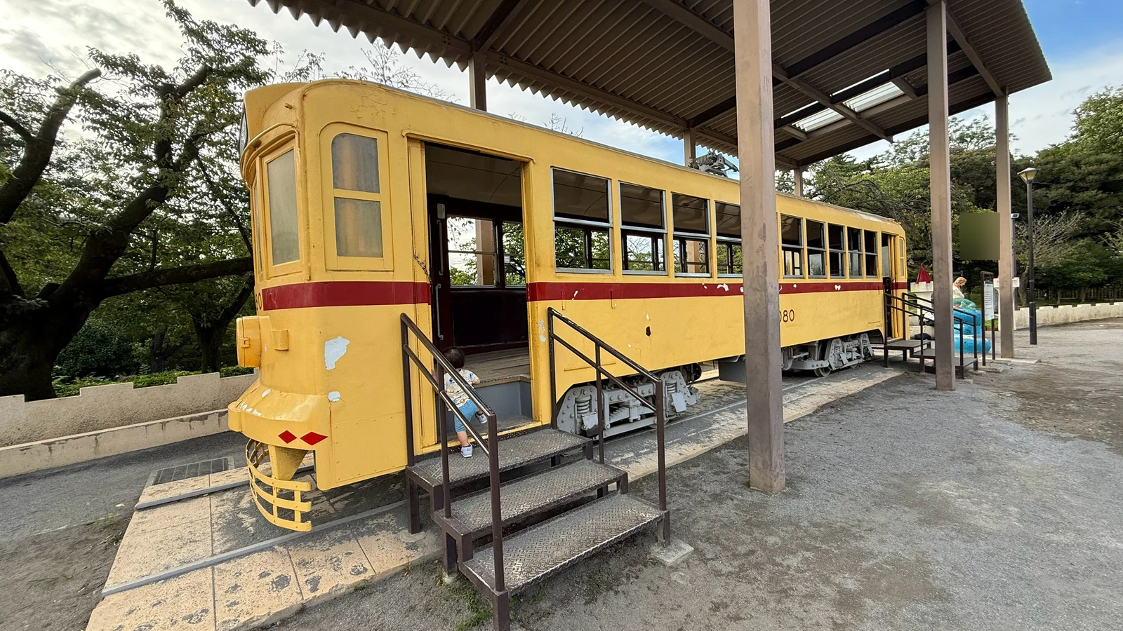 屋根の下に展示された黄色い都電6080と乗車用階段