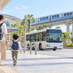 親子が駅前の交通広場でバスとモノレールへ向かうAI生成イメージ