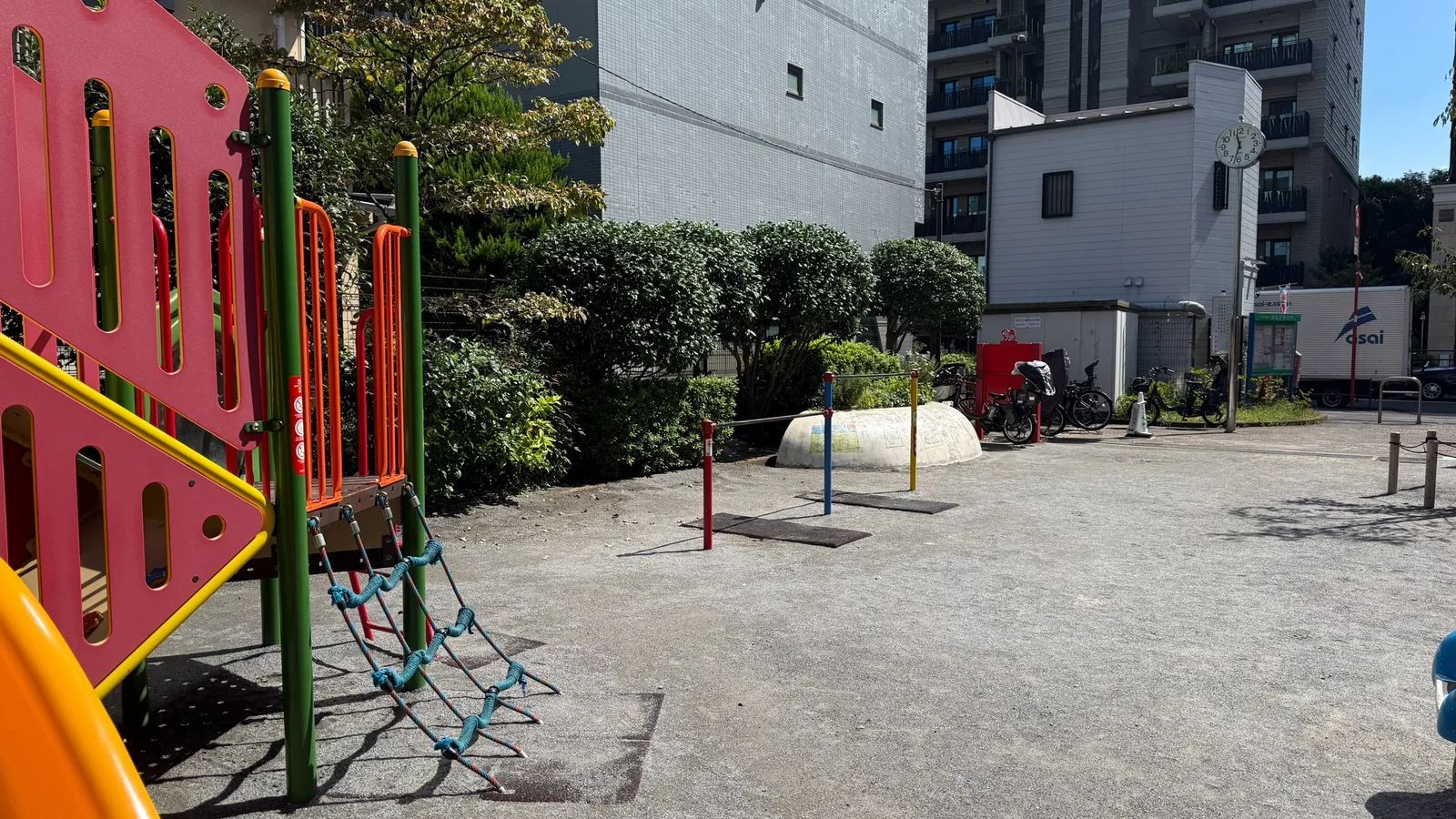複合遊具の横に広がる園内と周辺の建物