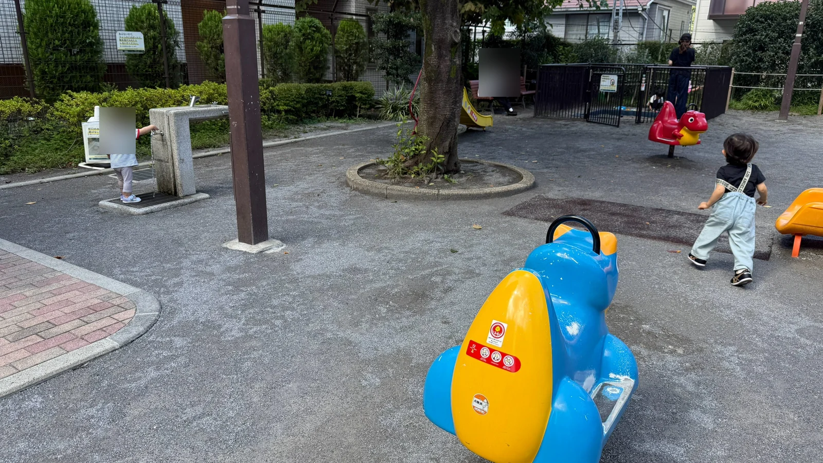 木の周囲の広場と揺れる乗り物が並ぶ白台児童遊園