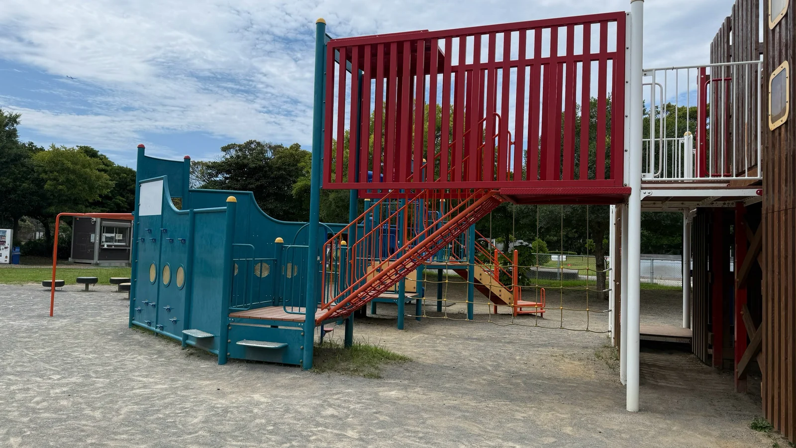赤い手すりの階段と青い船体でできた大型の複合遊具